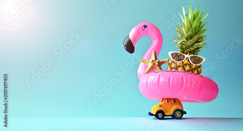 Pink inflatable flamingo on toy car and pineapple. Summer pool float party idea. Summer concept.