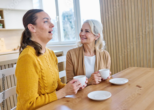 Portrait of mother and daughter  having fun, chating drinking coffee, sitting and hugging  at home, family life, parenting, love and bonding concepts