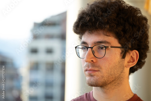 Cuadro en lienzo Young man with curly hair and glasses in profile, silently contemplating while l