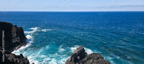 Foto Rocky coastline with waves crashing against dark cliffs, showcasing the vast oce