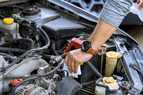 Slika na platnu Man works on car engine in garage to perform maintenance check for issues