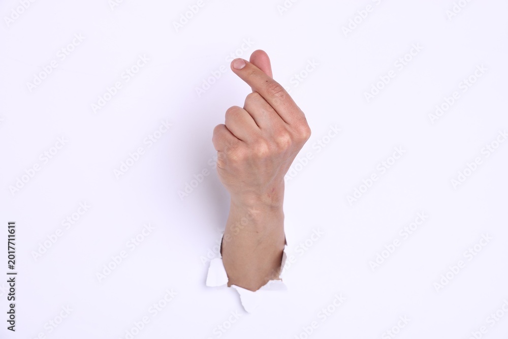 Naklejka premium Man showing heart gesture with fingers through hole in white paper, closeup