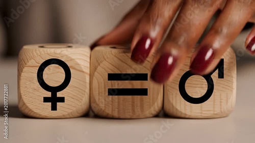 Gender equality concept: hand rotating wooden dice with female and male symbols