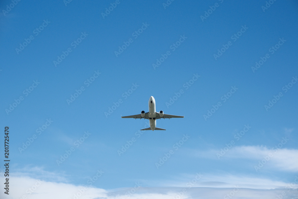 Fototapeta premium White Airplane Taking Off Against Blue Sky and Clouds
