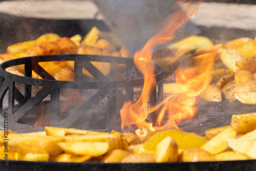 Kartoffelscheiben auf einem Griller mit Flammen in der Mitte