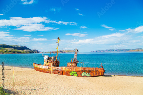 Foto An old fishing vessel washed ashore by a storm on the shore of the Barents Sea