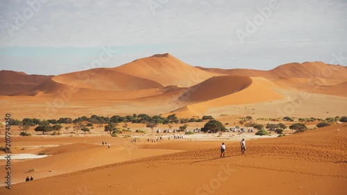 Tourists climbing impressive sand dunes of Sossusvlei and Dead Vlei in Namib Naukluft National Park, iconic travel destination in the heart of Namibia