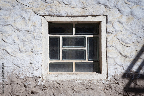 Abstract glass brick window, grey house wall with shadow on it, sunny day with no person