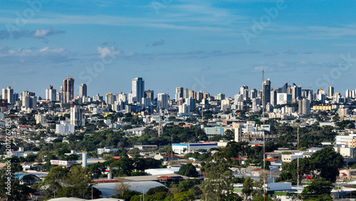 General drone view of the city of Cascavel, western region of Parana, showing the buildings, houses, and wooded areas on a slightly sunny day.