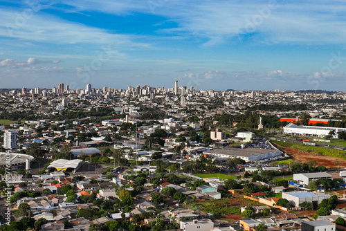 General drone view of the city of Cascavel, western region of Parana, showing the buildings, houses, and wooded areas on a slightly sunny day.