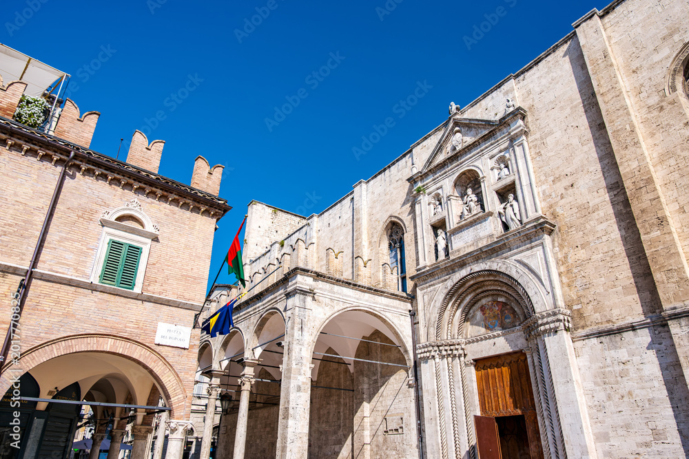 Fototapeta premium Historic piazza in Ascoli Piceno with the Palazzo dei Capitani and San Francesco church along the logge, medieval and Renaissance facades under a clear blue sky