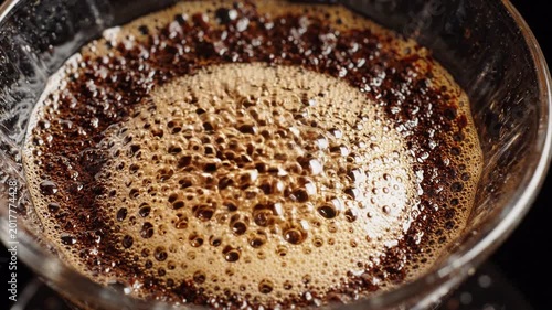 Closeup overhead view of coffee brewing in a pour over dripper, rich brown grounds and fresh crema forming, dark background, morning ritual