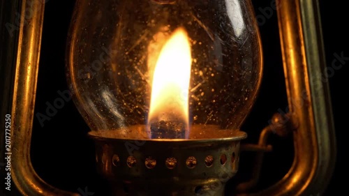 Close up of a vintage oil lantern burning with a bright warm flame, casting a cozy glow, perfect for rustic or historical themes