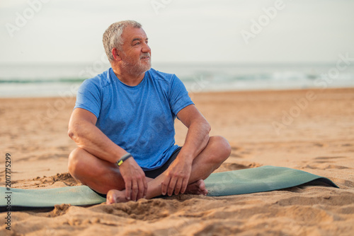 Senior man meditating on beach for healthy retirement