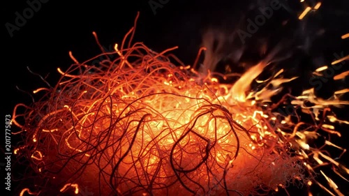 Burning embers with orange sparks flying and wisps of smoke rising from a dark background, abstract fiery energy