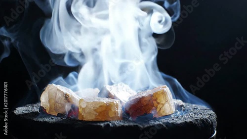 Crystals glowing with heat and smoke rising dramatically against a dark backdrop, representing energy release or chemical reactions