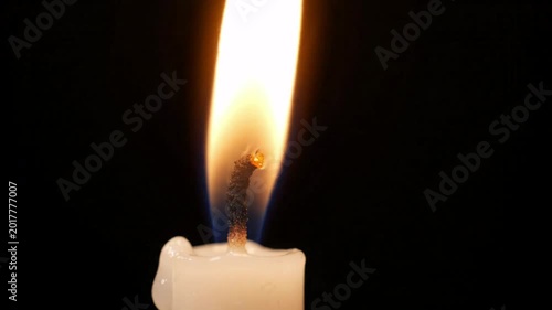 Closeup of a white candle flame flickering against a black background, gentle heat and light, subtle blue glow at the base of the fire, peaceful ambiance