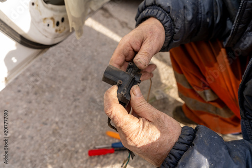 Replacing the central locking motor in a front door. A close-up of a technician's hands holding the central locking motor.