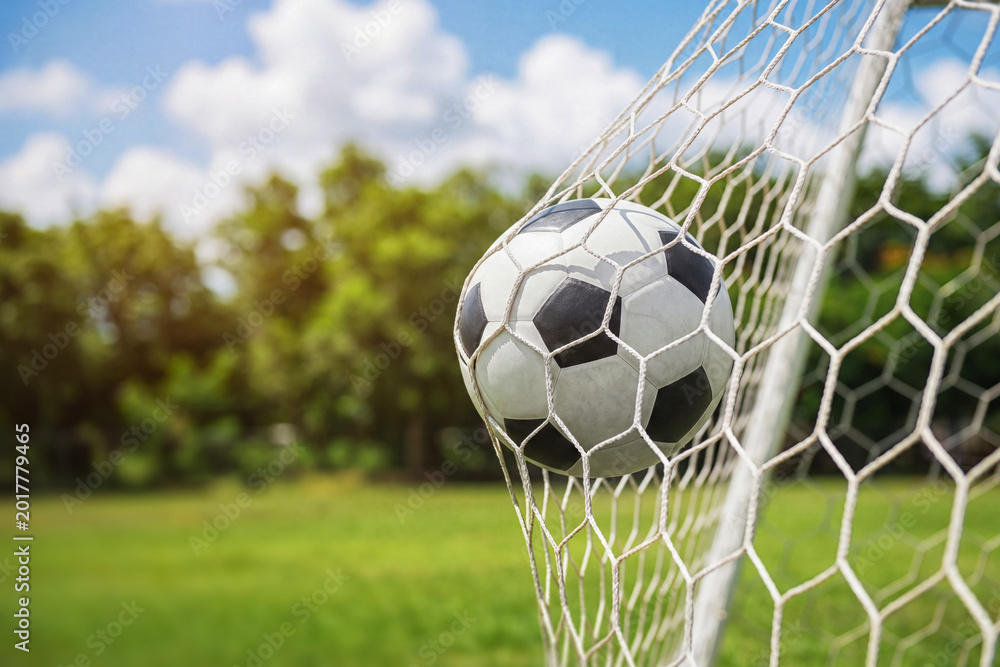 Naklejka premium Soccer ball in soccer goal net . Close-up textured soccer net on soccer goal.