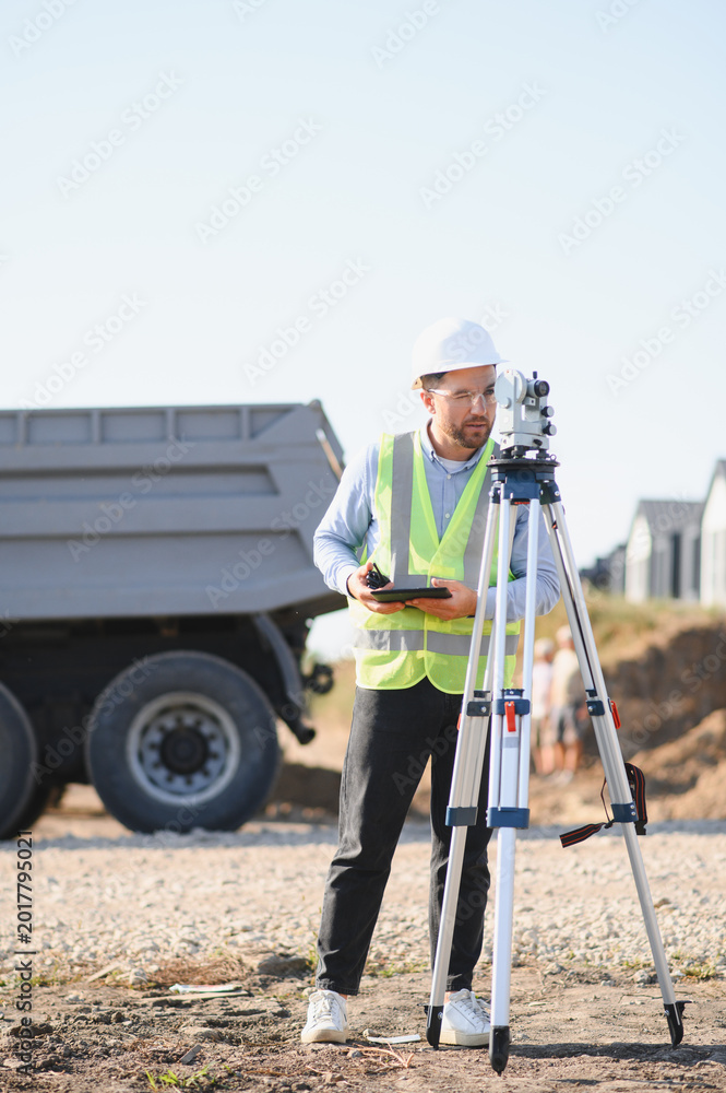 Naklejka premium Surveyor man working with digital tablet and total station