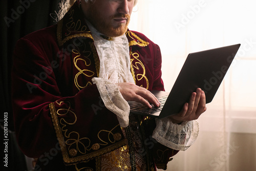 Quadro em tela young man wearing historical costume using laptop, blending past era styling with modern technology