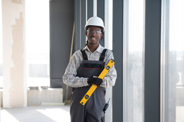 Construction worker holding spirit level smiling at construction site