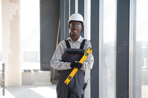 Foto Construction worker holding spirit level smiling at construction site