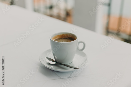 Cup of black coffee on a white table in a street cafe. Selective focus.