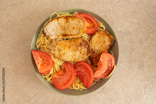Schilderij op canvas Top view of grilled pork steaks with spaghetti pasta and fresh tomato slices for