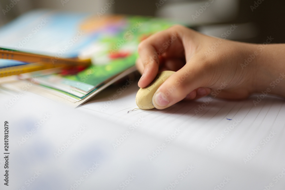 Foto Child hand erasing mistake on notebook homework