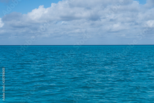Calm blue ocean under blue sky with puffy clouds