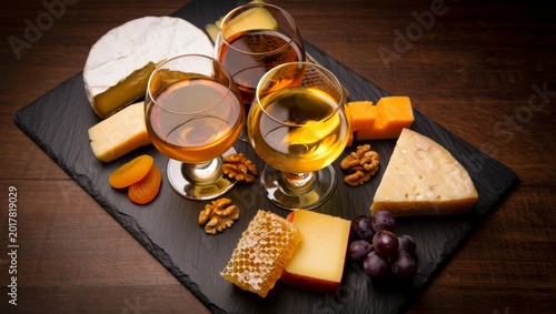 Assorted cheeses, cognac glasses, walnuts, grapes, dried apricots, and honeycomb creating a rich gourmet experience