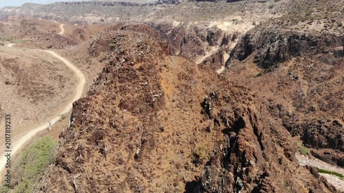 Aerial video flight over rugged mountains and a dry rocky wadi canyon on socotra island yemen, perfect for desert travel documentaries, exploration vlogs or alien backgrounds