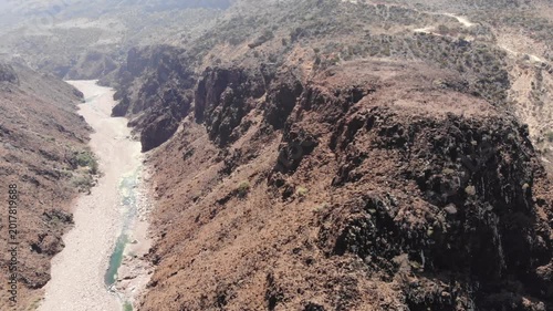 Aerial video flight over a deep rocky canyon and dry wadi riverbed on socotra island yemen, perfect for desert travel documentaries, nature exploration or alien landscape backgrounds