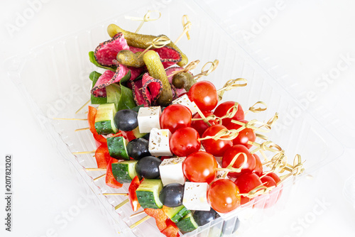 Gourmet appetizer skewers with vegetables cheese olives and salami in plastic container