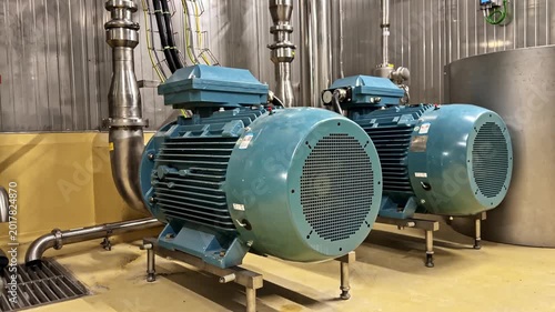 Industrial electric motors and pumps aligned on factory floor in mechanical facility