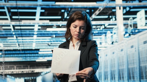 Foto Data center manager verifying infrastructure status with clipboard files and holographic visuals
