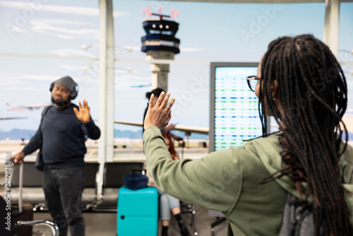 Foto Black boyfriend and girlfriend sharing bittersweet farewell at airport gate, waving goodbye before going separate ways