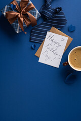 Happy Father's Day gift with tie, card, wrapped present, ribbon and coffee on vertical blue background