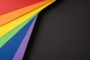 Colorful rainbow paper layers on black background for Pride Month celebration and inclusion concept