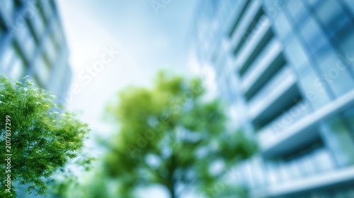 Looking up between modern buildings and lush green trees on a bright day