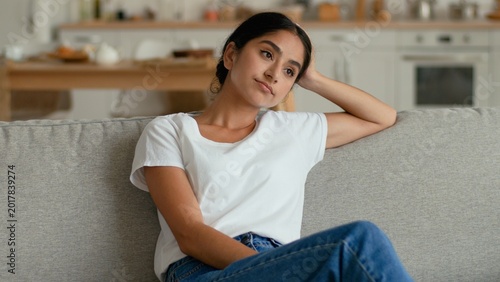 Tableau sur toile Sad stressed pensive Indian Arabian woman at home sitting sofa thinking worried
