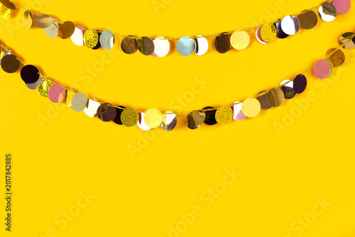 Metallic sequin disc garland strands on yellow background.