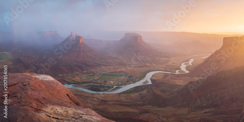 Aerial view of the winding Colorado River flowing through the red rock mesas and buttes of Castle Valley under a misty golden sky Castle Valley, Utah, United States.