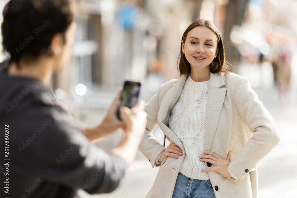 Obraz premium Man takes photo of cheerful woman on a street in a spring city