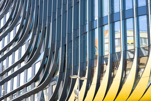 Photos Modern architectural facade featuring curved glass panels and reflective surface