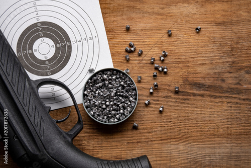 Airgun and pellet on wooden table.