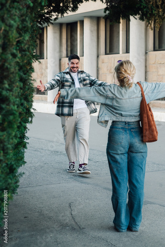 Konstfotografi Happy young diverse couple reuniting outdoors, embracing with open arms, meeting