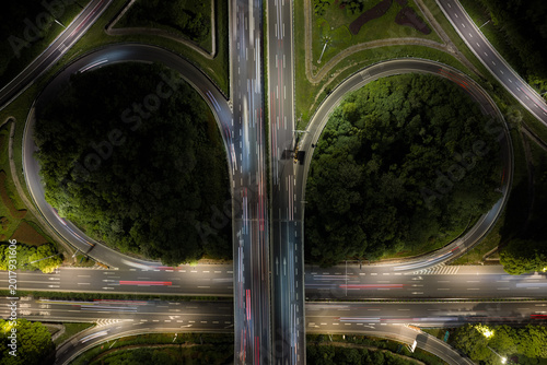Aerial view of symmetrical highway interchange at night with vibrant light trails