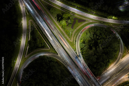 Aerial view of symmetrical highway interchange at night with vibrant light trails
